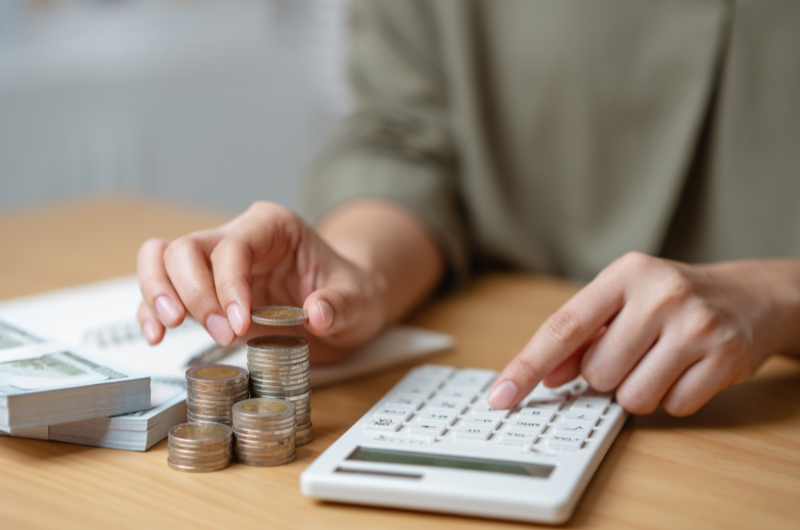 Some os ganhos e subtraia os gastos | Mãos empilhando moedas e usando calculadora | Eu Dou Conta | Blog da Tenda 