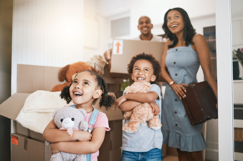 Vai mudar de cidade | Crianças sorrindo segurando bichos de pelúcia enquanto os pais carregam caixas de mudança | Onde morar | Blog da Tenda