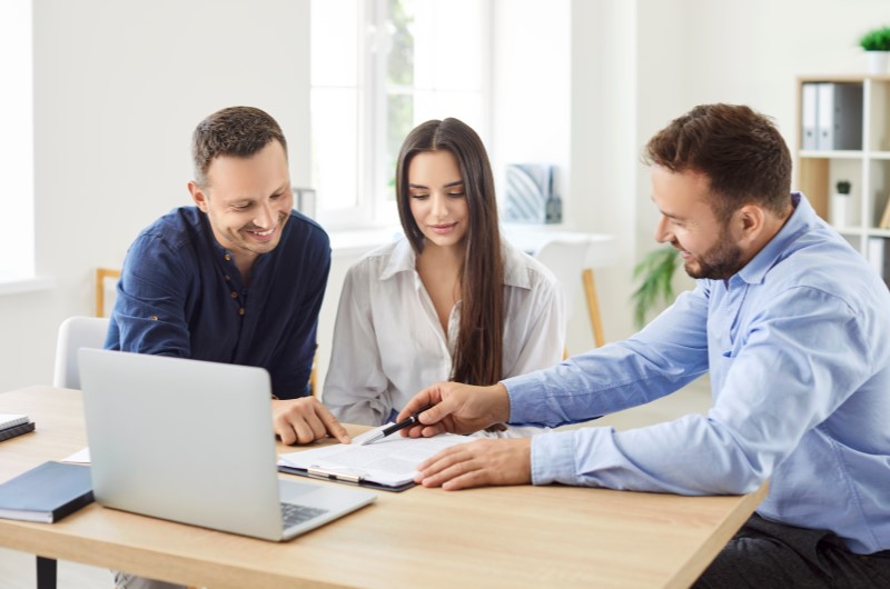 Como funciona a transferência de imóvel | Homem orientando casal a assinar um contrato | Trilha da Conquista | Blog da Tenda