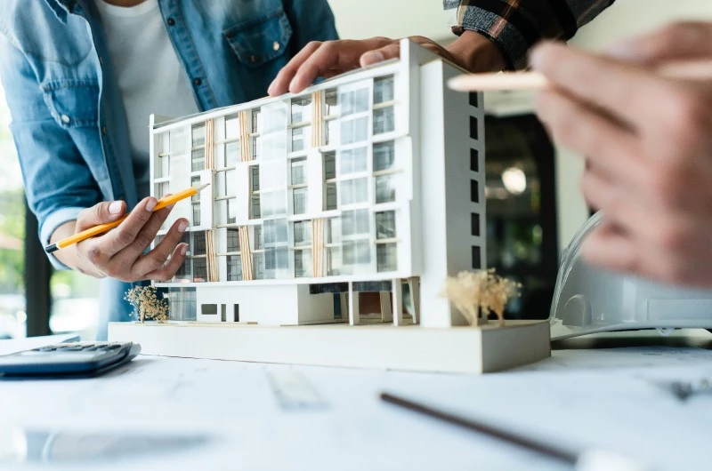 Condomínio comercial ou industrial | Arquitetos analisando maquete de edifício moderno | Viver em Condomínio | Blog da Tenda 