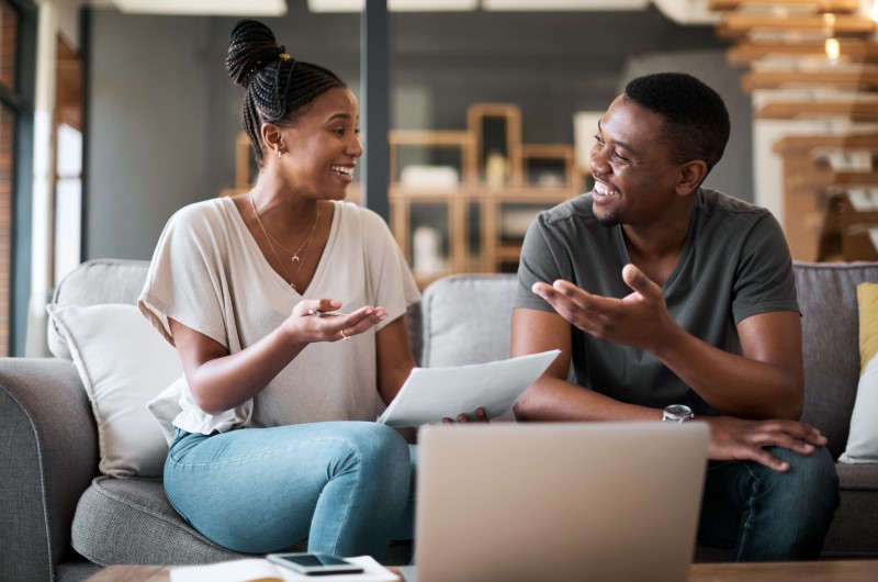 Defina metas | Casal sorrindo enquanto organiza finanças | Eu Dou Conta | Blog da Tenda 