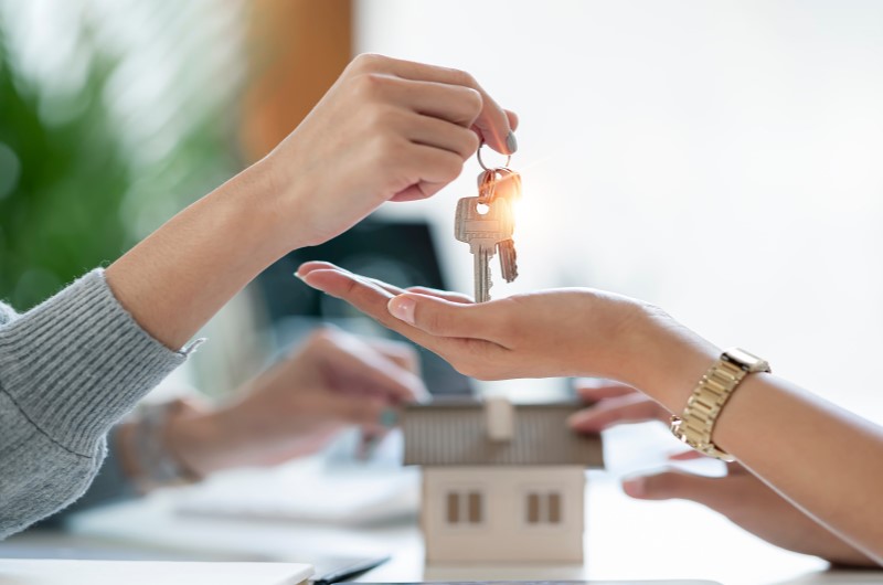 Doação | Uma pessoa entregando chave de casa para outra pessoa | Trilha da Conquista | Blog da Tenda