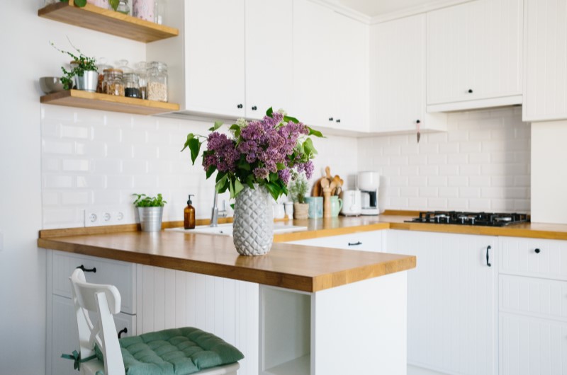 Vantagens da cozinha em conceito aberto | Cozinha branca decorada com vaso de flores | Casa e Decoração | Blog da Tenda 