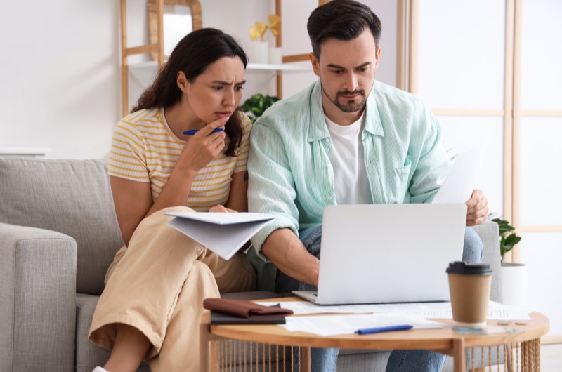 Avalie seu orçamento | Casal preocupado revisando contas no notebook | Trilha da Conquista | Blog da Tenda 