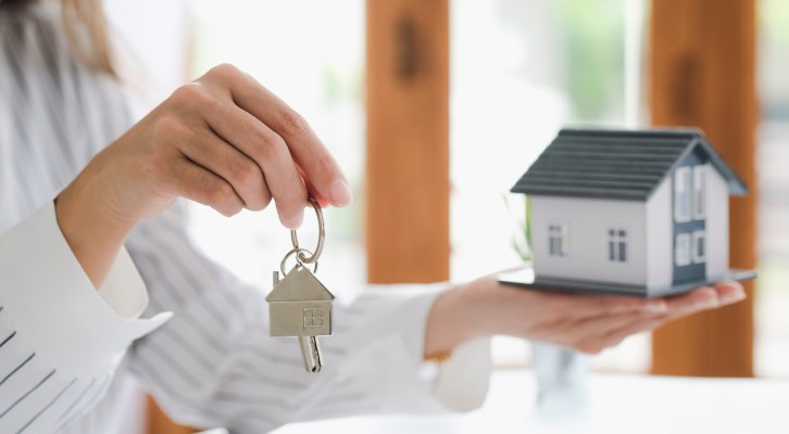 Diferença entre bairro residencial e comercial | Mulher segurando casinha e chave nas mãos | Onde Morar | Blog da Tenda