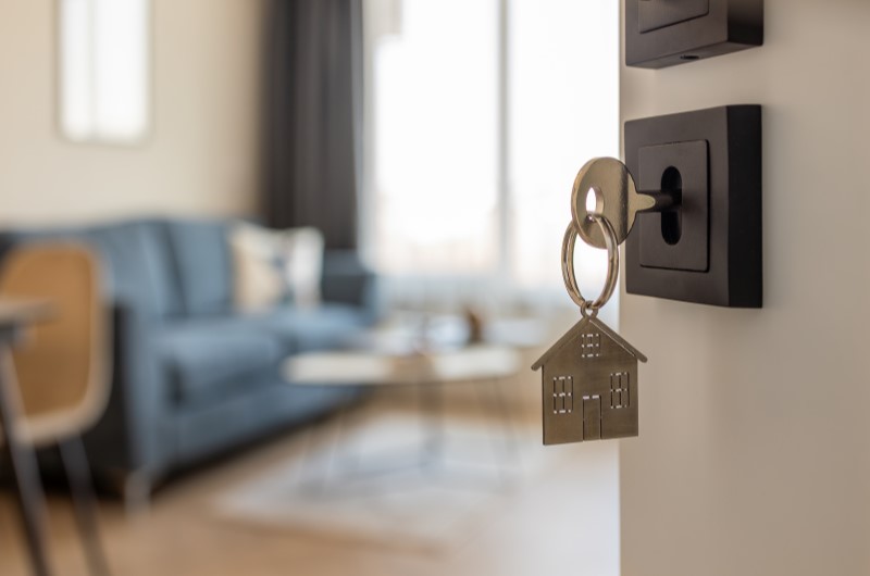 É possível financiar um imóvel sem entrada | Chave pendurada na porta com pingente de casa | Trilha da Conquista | Blog da Tenda 