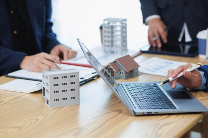 O que é uma administradora de condomínios | Profissionais analisando maquetes e gráficos no escritório | Viver em Condomínio | Blog da Tenda 