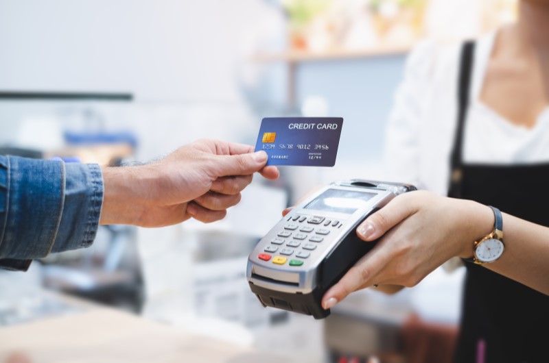 Cartão de crédito | Foto de uma pessoa passando o cartão de crédito na maquininha | Como limpar o seu nome 