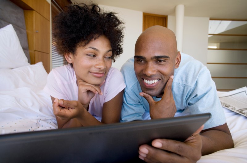 Empréstimo | Foto de um casal feliz pesquisando no computador | Como limpar o seu nome | Eu Dou Conta