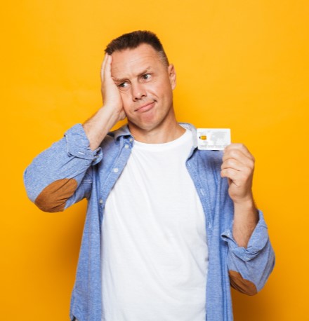 Homem preocupado segurando o seu cartão de crédito | Financiamento para negativado | Como limpar o seu nome | Eu Dou Conta