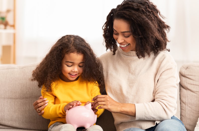 Aprenda a economizar | Mãe e filha colocando moedas em um cofrinho | Eu Dou Conta