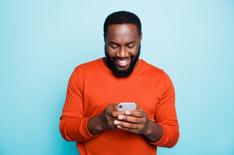 Como escolher o melhor programa de afiliados | Homem sorrindo para o celular | Economia e renda extra | Eu Dou Conta