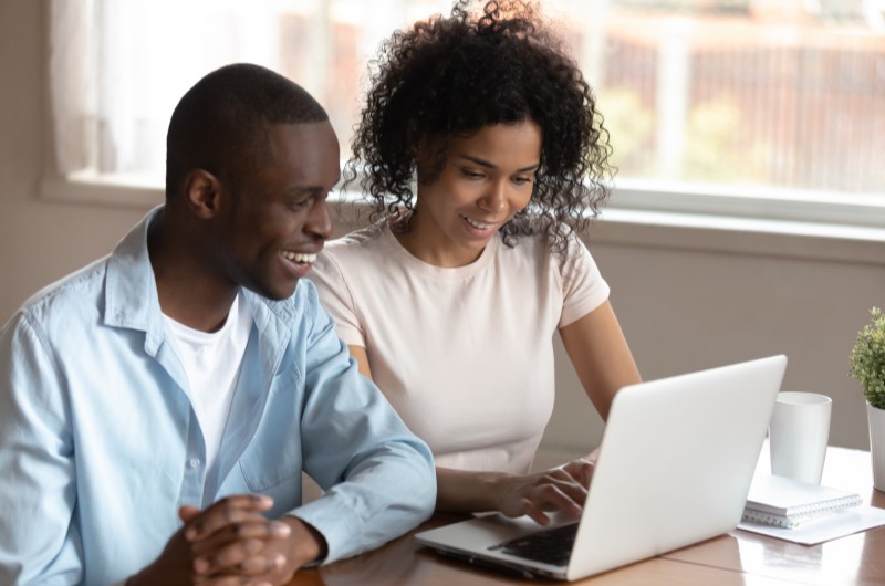 Como montar um programa de afiliados | Foto de um casal sorrindo em frente ao computador | Economia e renda extra | Eu Dou Conta