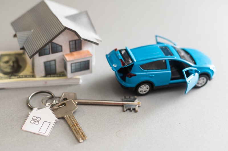 Tipos de financiamento | Foto de uma miniatura de carro, casa, notas de dinheiro e chaves de casa | Dúvidas sobre dívidas | Eu Dou Conta