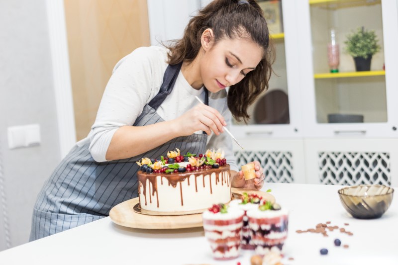 Faça bolos de aniversário para vender | Foto de uma mulher decorando bolo de aniversário | Economia e renda extra | Eu Dou Conta