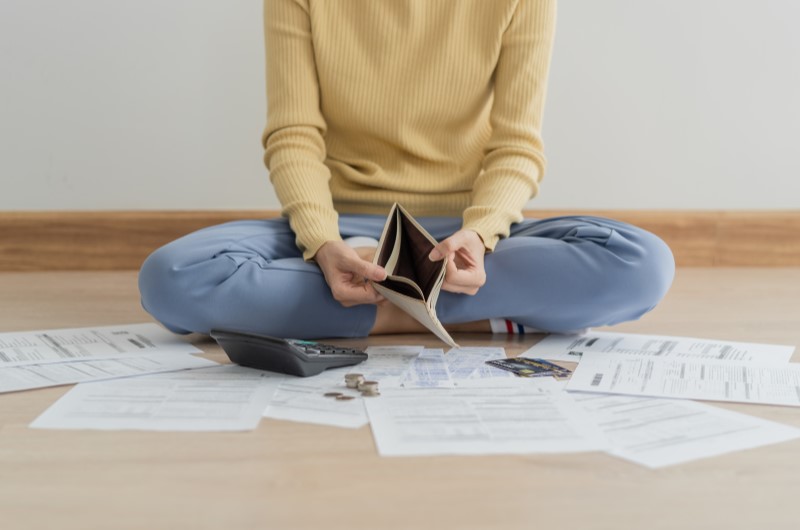 Como montar uma reserva de emergência com dívidas | Foto de uma mulher mostrando a carteira vazia e com dívidas | Economia e renda extra | Eu Dou Conta