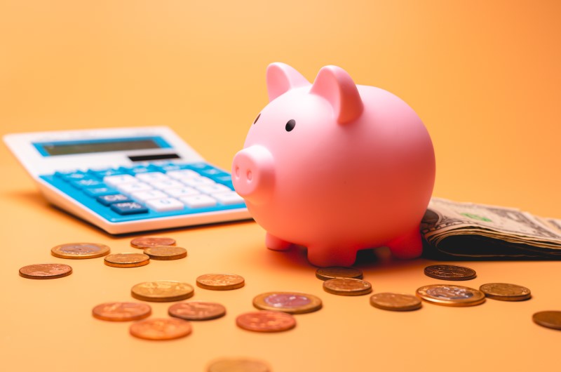 Como sair das dívidas | Foto de um cofrinho de porquinho, calculadora e moedas | Dúvidas sobre dívidas | Eu Dou Conta