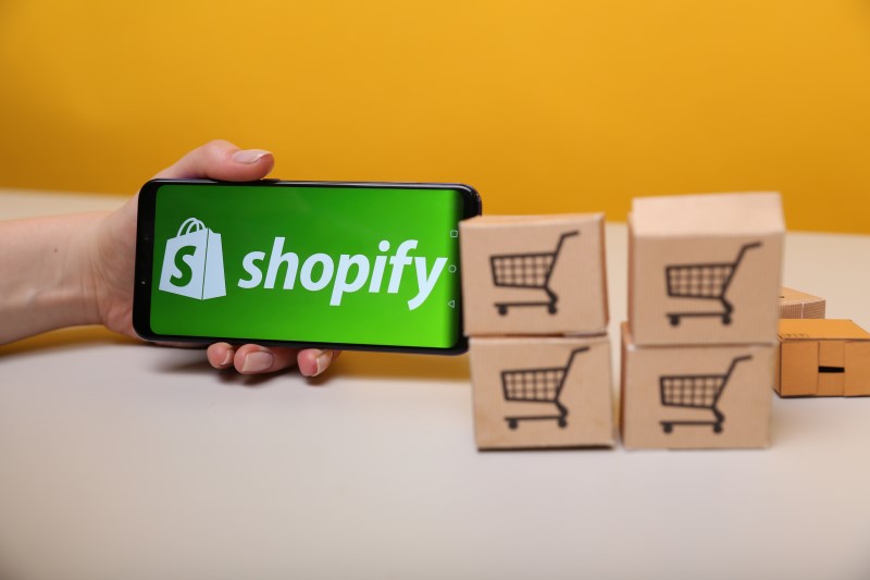 Como ser um afiliado do Shopify | Foto de um celular com o logo da Shopify e caixinhas | Economia e renda extra | Eu Dou Conta