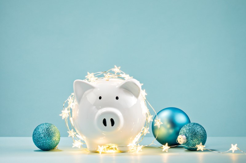 Dicas para sair das dívidas até o final do ano | Foto de um cofrinho de porquinho com decoração de Natal | Como limpar o seu nome | Eu Dou Conta