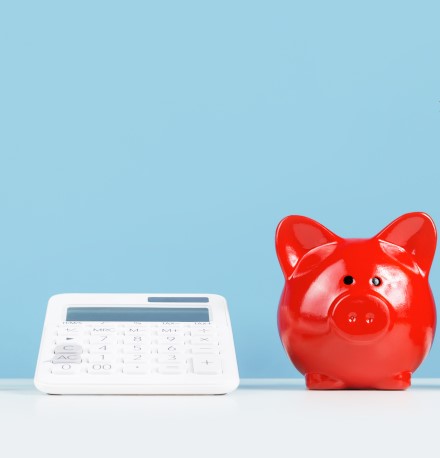 Capa Desktop Como juntat dinheiro | Foto de um cofrinho vermelho, uma calculadora, um bloco de notas e um porta lápis | Economia e renda extra | Blog Eu Dou Conta