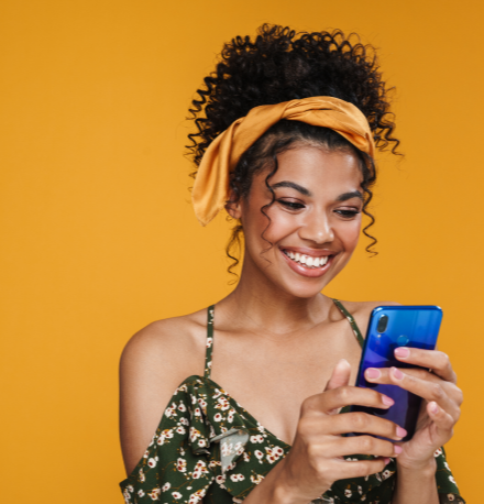O que é análise de crédito? Saiba como funciona e como ser aprovado | Foto de uma mulher sorridente enquanto usa o celular | Dúvidas sobre dívidas | Eu Dou Conta