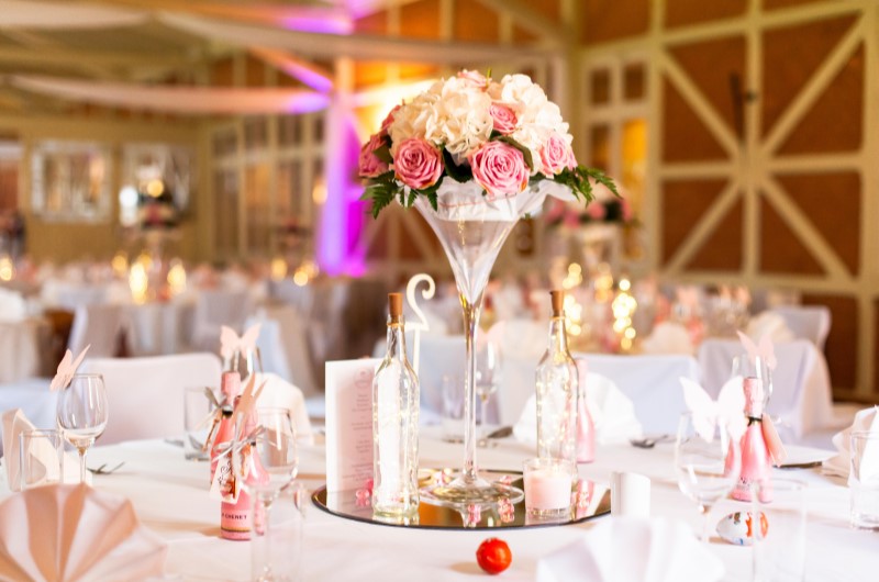 Comece a pesquisar os espaços para a cerimônia | Foto de um salão decorado para um casamento, com flores e decorações rosa e branco sobre a mesa | Economia e renda extra | Eu Dou Conta 