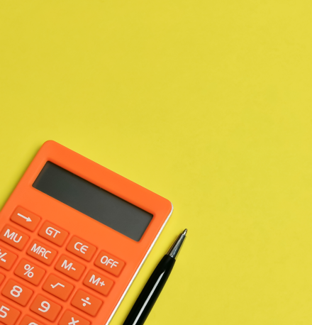 O que é consórcio? Confira o guia completo | Foto de uma calculadora e uma caneta em um fundo amarelo | Dúvidas sobre dívidas | Eu Dou Conta