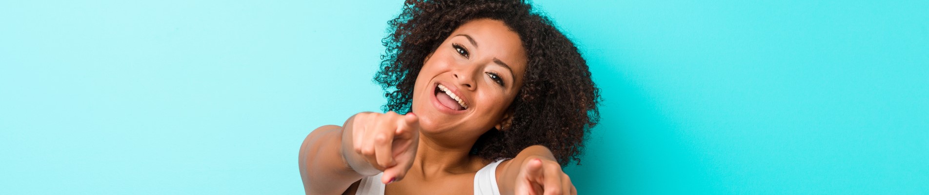 8 dicas para economizar energia no verão e gastar menos | Foto de uma mulher sorridente apontando para frente, em um fundo azul | Economia e renda extra | Eu Dou Conta