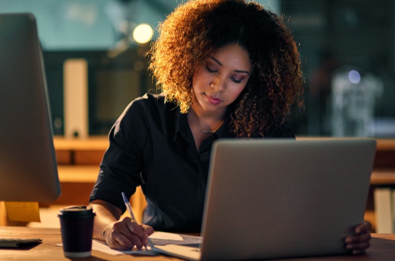 O que é um MEI (Microempreendedor Individual)? | Foto de uma mulher usando o notebook, enquanto escreve em um papel | Economia e renda extra | Eu Dou Conta 