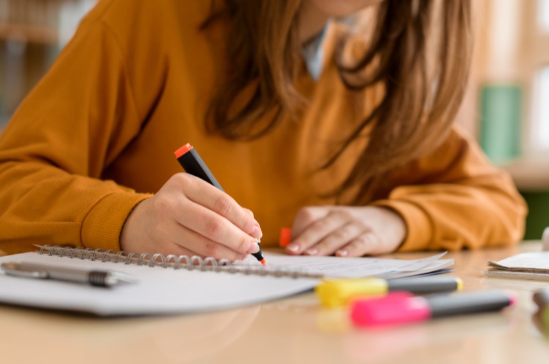 Qual a importância da educação financeira? | Foto de uma moça escrevendo em um caderno enquanto estuda | Economia e renda extra | Eu Dou Conta 