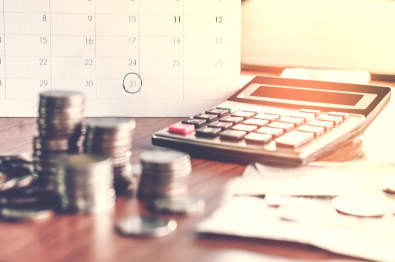 Defina metas financeiras | Foto de uma calculadora, moedas e um calendário | Economia e renda extra | Eu Dou Conta 