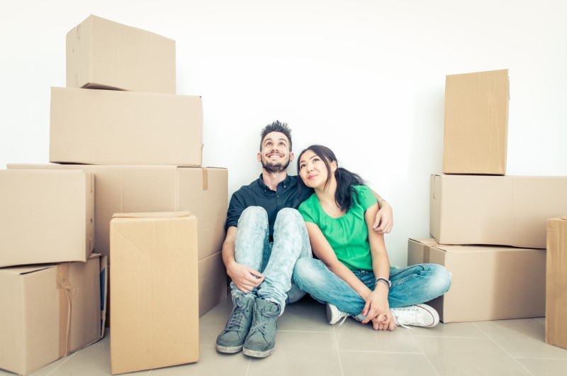 Utilize o Minha Casa, Minha Vida | Foto de um casal feliz sentado na casa nova, cercado por caixas | Economia e Renda Extra | Eu Dou Conta 