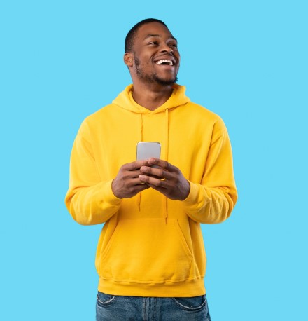 Compras por impulso: 14 dicas de como evitar e não se endividar | Foto de um homem sorridente segurando o celular | Economia e renda extra | Eu Dou Conta