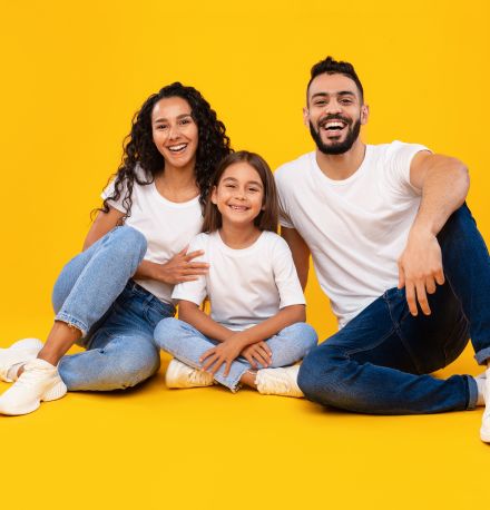 Orçamento familiar: 13 dicas para montar o seu | Foto de uma família feliz e sorridente sentada no chão | Economia e Renda Extra | Eu Dou Conta