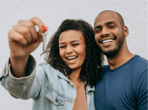 Casal sorrindo segurando a chave do imóvel | O que é subsídio | Tenda.com