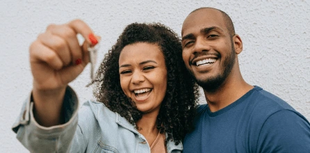 Casal sorrindo segurando a chave do imóvel | O que é subsídio | Tenda.com